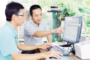 六月十六日,郑忠光(右)在与收胶记账员交流合作