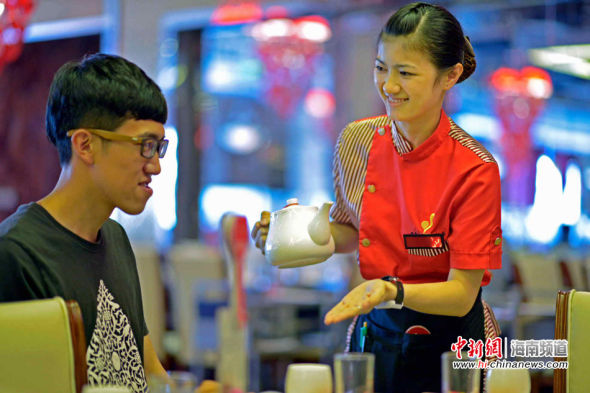 图为餐厅服务员面带笑容为客人服务.骆云飞摄