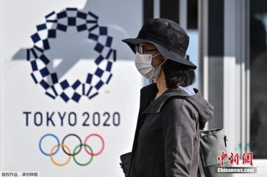 资料图：图为一名女士走过2020年东京奥运会海报。