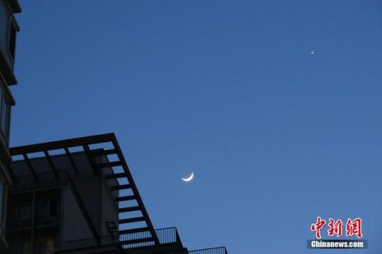资料图：2020年3月28日，北京，天气晴好，太阳落山之后，天宇“金星合月”天文景观清晰可见。中新社记者 孙自法 摄