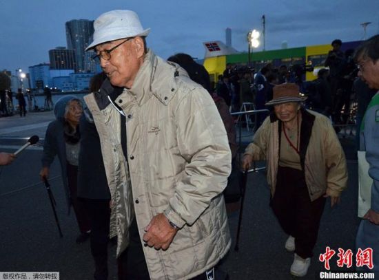 资料图：为防止台风侵袭，日本老年人抵达避难场所。