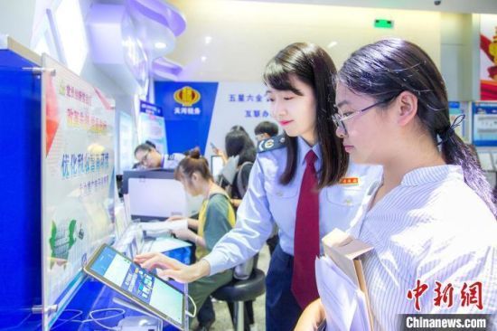 资料图：税务人员帮助纳税人通过电子税务办理业务。杨锐轩 摄