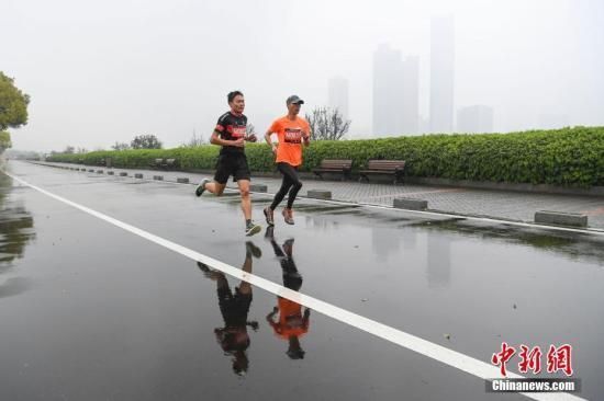 资料图：跑步爱好者在雨中奔跑竞技。 中新社记者 杨华峰 摄