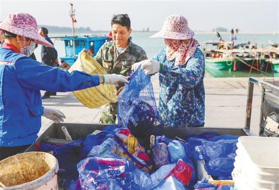 在昌江黎族自治县昌化港码头，渔民钟强彬将渔网上清理的垃圾置换积分。本报记者 李天平 摄