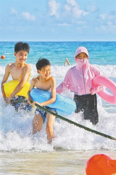 7月15日，家长带着小朋友在三亚大东海冲浪。王程龙 摄