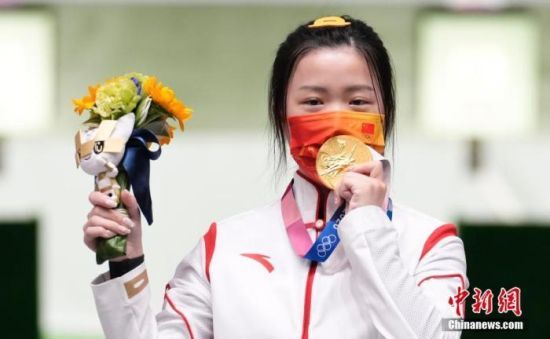 东京奥运会女子10米气步枪决赛中，中国选手杨倩夺得冠军，为中国代表团揽入本届奥运会第一枚金牌。这也是本届东京奥运会诞生的首枚金牌。图为杨倩隔着口罩亲吻金牌。中新社记者 杜洋 摄