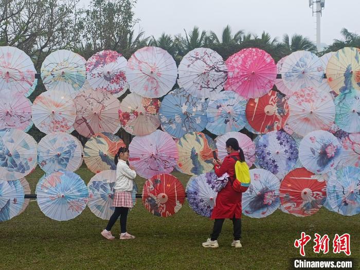 2月3日，“我们的节日·元宵游园会”在海口万绿园拉开帷幕。图为市民游客在油纸伞墙前合影留念。　张月和　摄