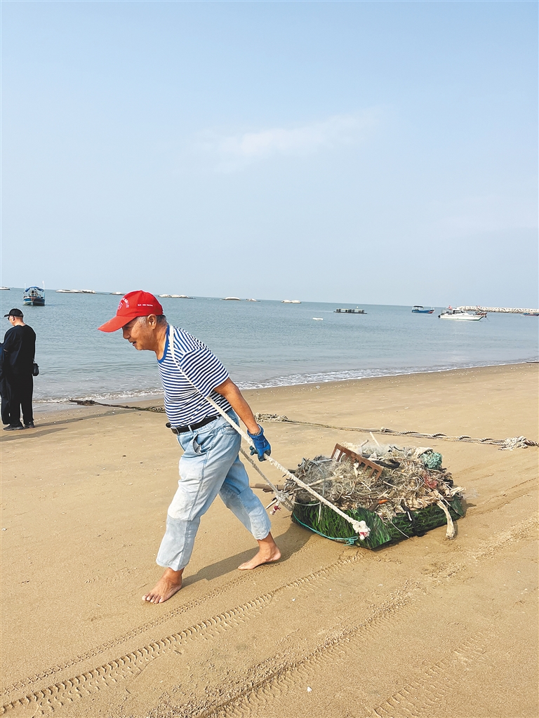 汪敏江在海边捡垃圾。本报记者 周月光 摄