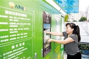 10月26日下午，在秀英区的海悦东方小区内，一位居民将打包好的厨余垃圾丢进“大胃蛙”厨余垃圾处理器。 本报记者 陈长宇 摄