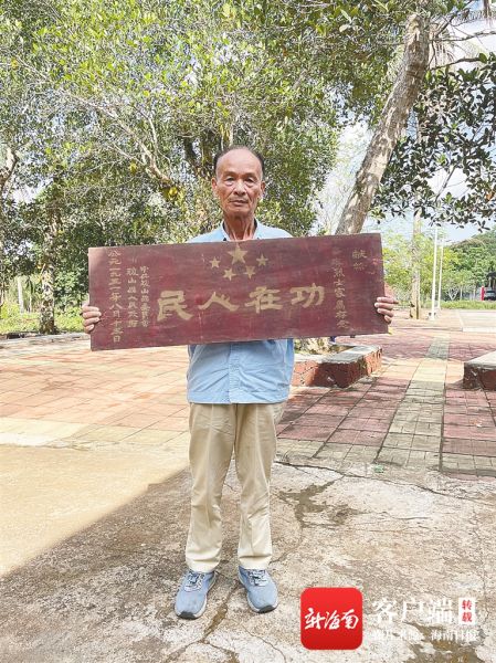 海口三门坡镇红明居村民举着"功在人民"的牌匾.