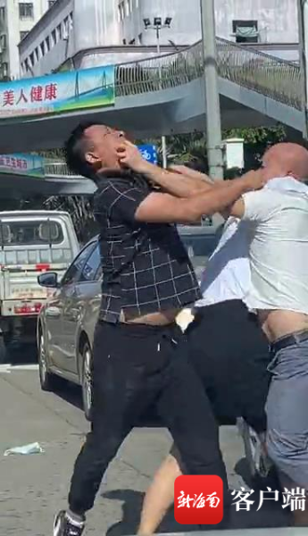 两男子扭打在马路中央,一女子尝试劝阻但始终无法将两人拦下.网友供图