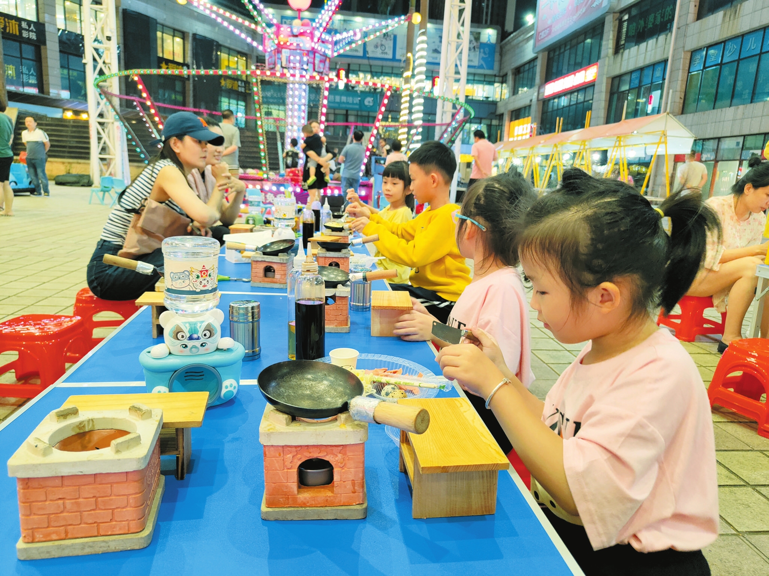 在友谊·国贸城市集的“迷你小厨房”摊位前，小朋友在认真做饭。 本报记者龙易强摄