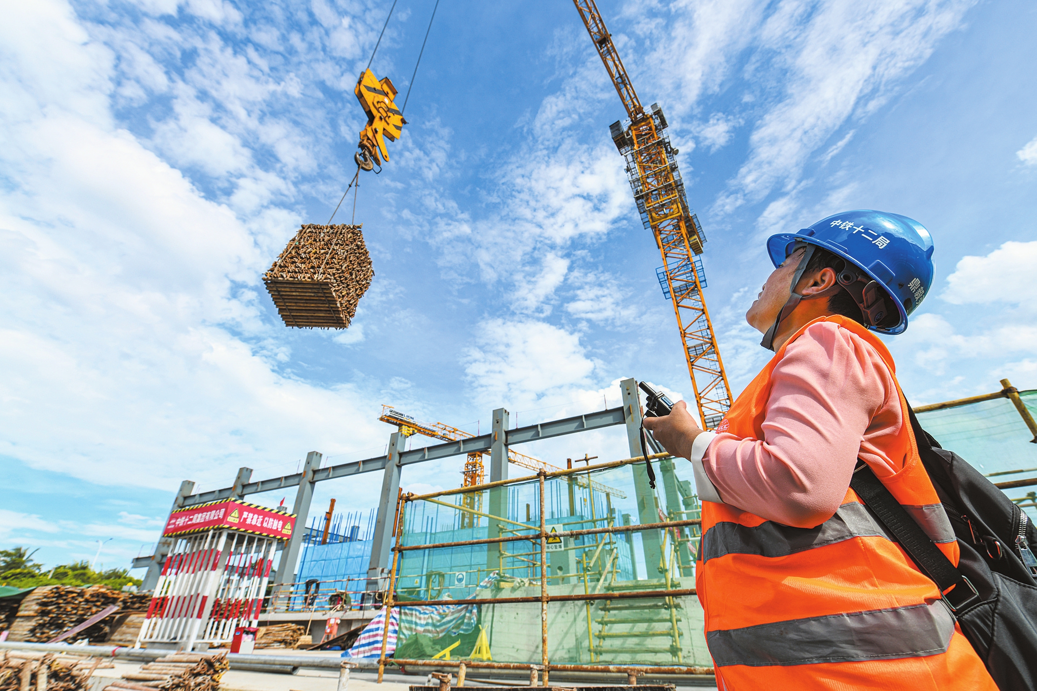 8月5日,在海南出版产业大厦项目现场,施工人员正在指挥吊装脚手架.