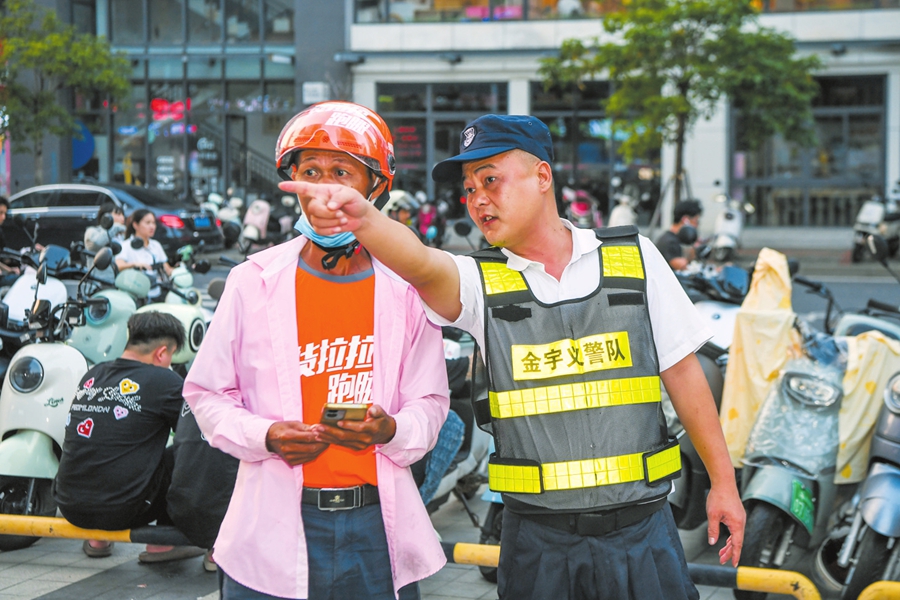 龙华区坡巷社区龙湖天街商圈周边,“义警队”队员在为市民指路。 本报记者康登淋摄
