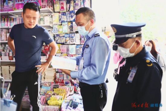 执法队员对文具店内的教辅书进行随机取样检查。